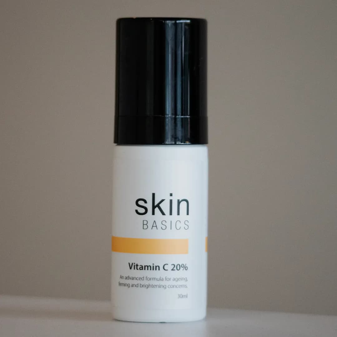 A white airless bottle of a client's white label Vitamin C 20% with an amber label band and a black cap