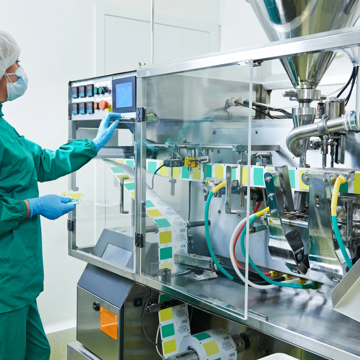 A technician in cleanroom gear at a filling line